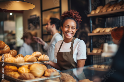 Attractive female seller puts fresh pastries on display and sells them to customers photo
