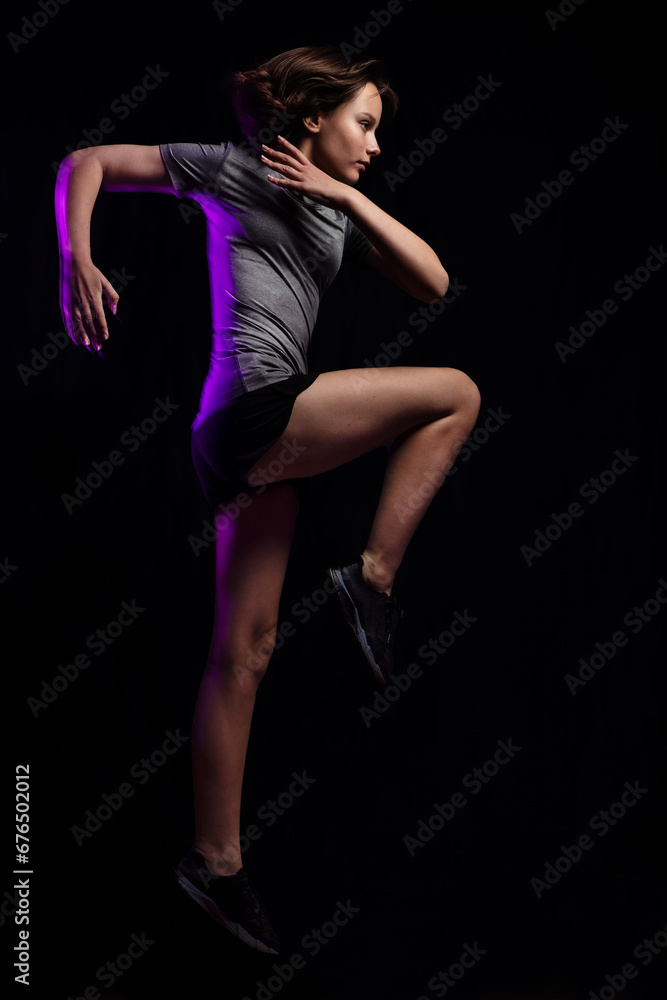 Teen girl athlete jumping against black background. Magenta motion blur is added purposefully