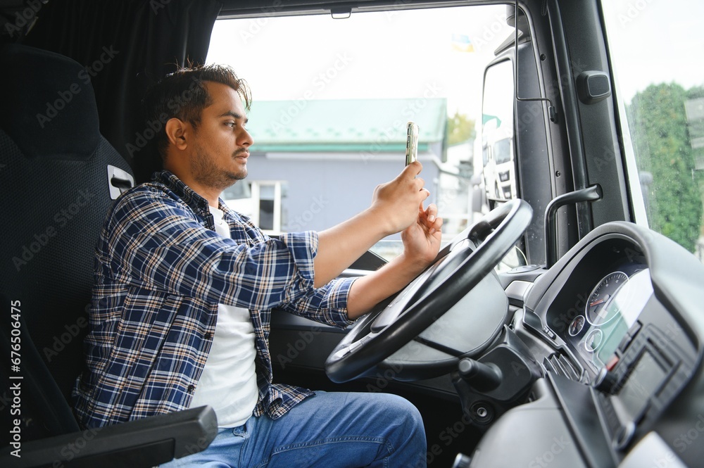 Obraz premium Young handsome indian man truck driver using smart phone