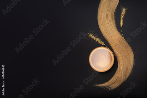 Blond long hair with cream jar and sprigs of ripe wheat. Healthy hair. Wheat serum oil for skin and hair care. Bottle of hair oil. Self-care, spa and wellness.