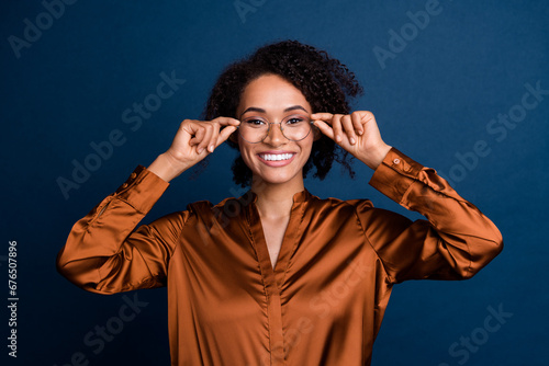 Photo of positive successful businesswoman ry new spectacles for good vision isolated over blue color background