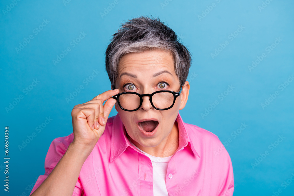 Portrait of speechless person wear stylish blouse touching eyewear staring at unbelievable discount isolated on blue color background Portrait of speechless person wear stylish blouse touching eyewear staring at unbelievable discount isolated on blue color background