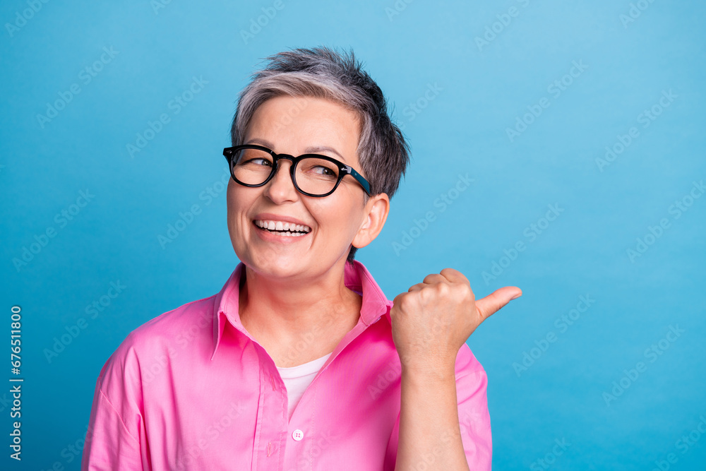 Portrait of positive cheerful person wear stylish blouse in eyewear indicating look at promo empty space isolated on blue color background Portrait of positive cheerful person wear stylish blouse in eyewear indicating look at promo empty space isolated on blue color background