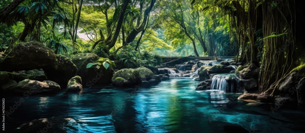 Naklejka premium In the lush green forest a picturesque waterfall cascades down the rocks its crystal clear water blending harmoniously with the tropical plants and leafy trees creating a breathtaking landsc