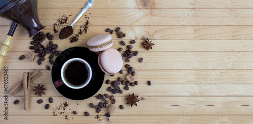 Black coffee in the brown cup, macaron, coffee beans and turk for making coffee on the wooden background. Copy space. Top view.
