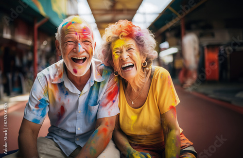a funny old couple, stained with colorful paint, smiling and having fun together. concept of happiness in middle age.