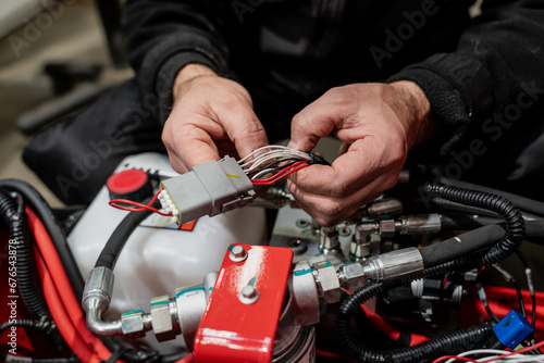 Electrician working on engine electric wiring close up with bare hands