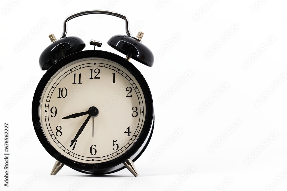 A black alarm clock with two bells on top, chrome handle, and legs, set against a white background. Timeless design meets functionality in this sleek, monochromatic timepiece. A black alarm clock with two bells on top, chrome handle, and legs, set against a white background. Timeless design meets functionality in this sleek, monochromatic timepiece.