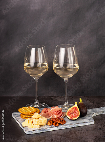Food photography of white wine; cheese; parmesan; fig; prosciutto, pecan, cracker, wineglass; bottle; chardonnay, sauvignon, winery