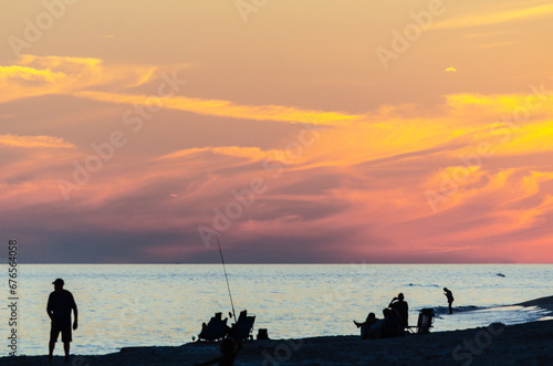 people enjoying the beach at sunset