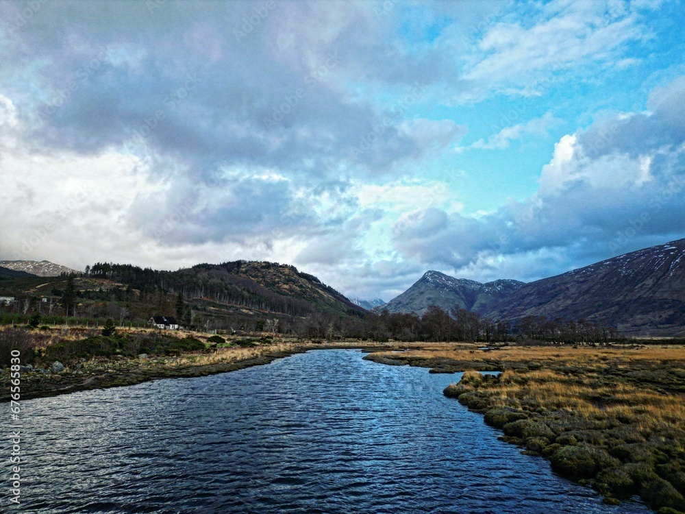Scenic shot of a river flowing through the Scottish highlands under the cloudy sky