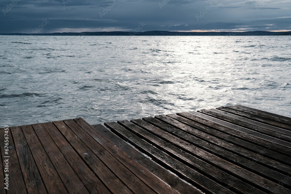 Wooden pier on the seashore with a cloudy sky in the background