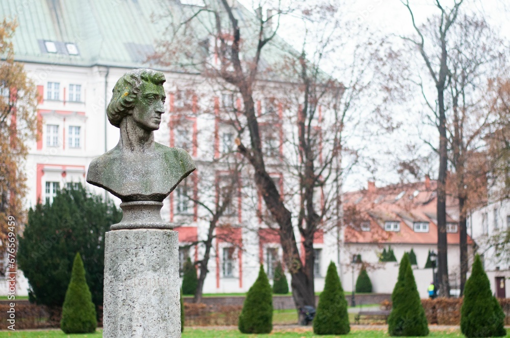Obraz premium Closeup of the Chopin statue with a building blurred background on a gloomy day in Poznan, Poland