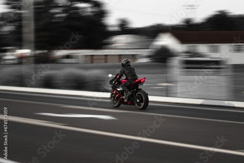 Biker driving fast with a motorcycle leaving the rest of the surrounding in blur © Wirestock