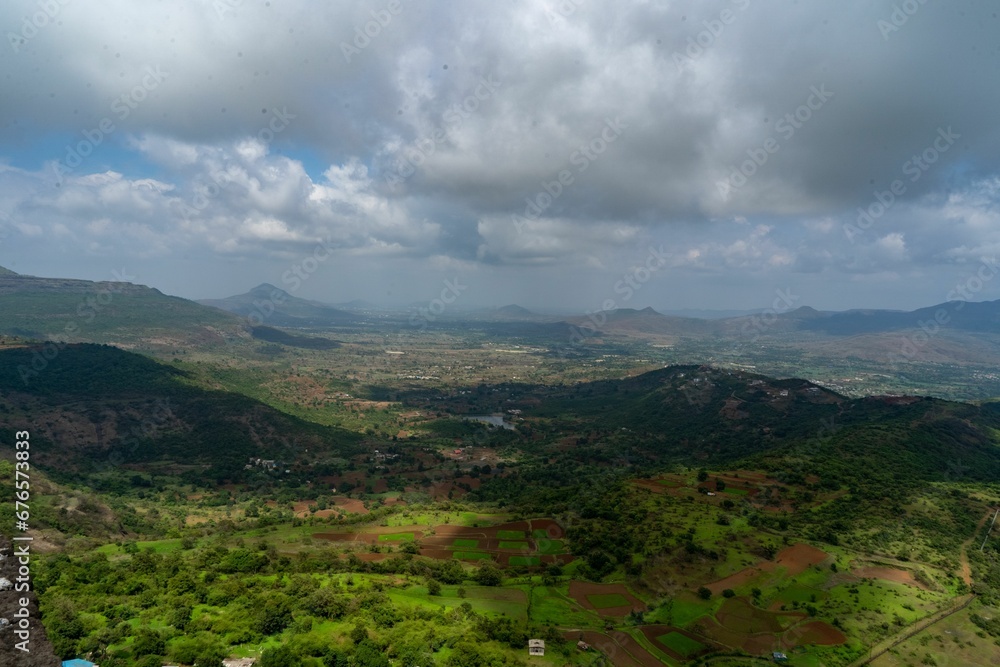 Naklejka premium Aerial shot of a rural area with cultivated farmlands and houses under the shadow of clouds