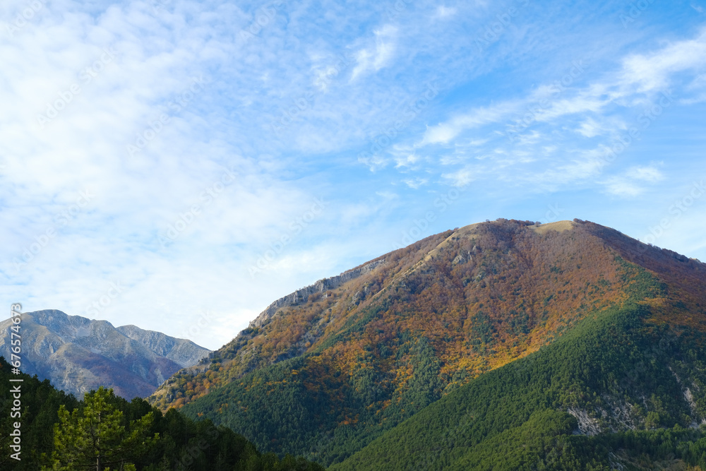 Mountain panorama covered half by autumnal orange and green trees in Pescasseroli, Abruzzo, Italy.