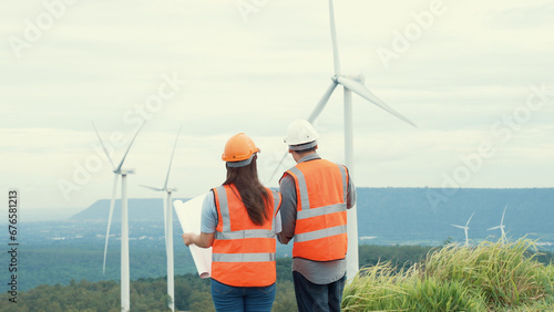 Male and female engineers working on a wind farm atop a hill or mountain in the rural. Progressive ideal for the future production of renewable, sustainable energy. © Summit Art Creations
