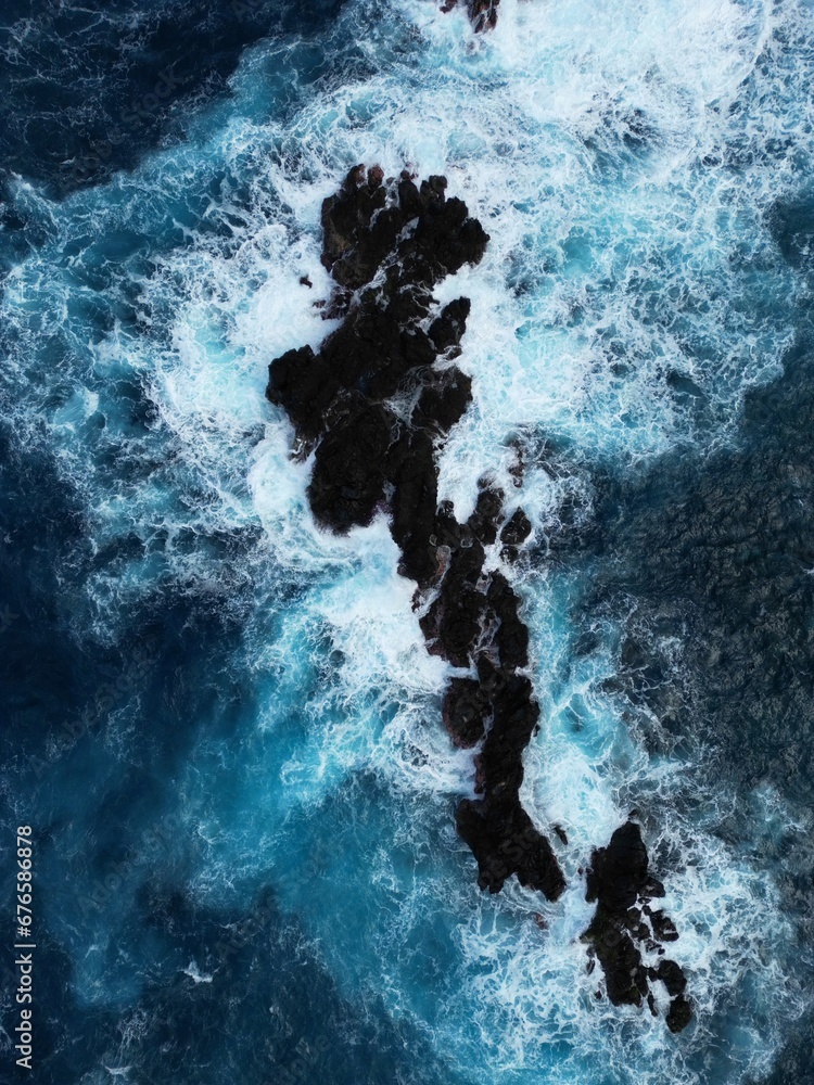 Potężne skały wystające z oceanu, obmywane falami wzburzonego oceanu. Huge rocks sticking out of the ocean, washed by the waves of the rough ocean - obrazy, fototapety, plakaty 
