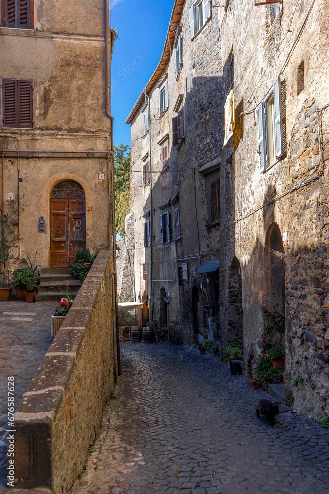 Vertical shot of a narrow paved street passing through old medieval residential buildings in Italy