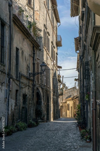 Vertical shot of a narrow paved street passing through old medieval residential buildings in Italy