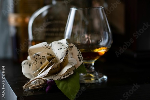 Closeup of sheet music boutonniere next to a glass of whiskey on the table