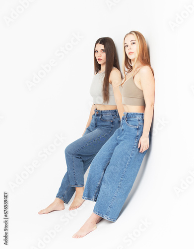 two young women friends isolated over white grey background