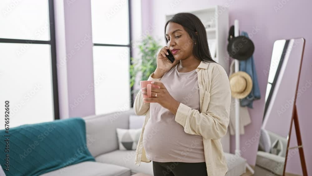 Young pregnant woman talking on smartphone drinking coffee at home Young pregnant woman talking on smartphone drinking coffee at home