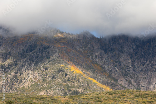 Low clouds hang over the peaks of Pine Valley Mountain in Southern Utah while the autumn gold of oak trees flows down the eastern slopes and the green of pines covers the western slopes.