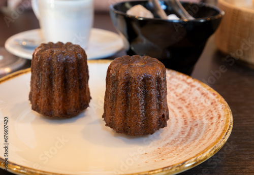 Canele, French pastry flavored with rum and vanilla, specialty of Bordeaux region, France, served with cup of black coffie in French restaurant
