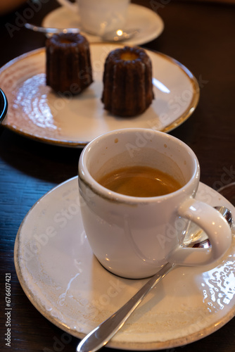 Fototapeta Naklejka Na Ścianę i Meble -  Canele, French pastry flavored with rum and vanilla, specialty of Bordeaux region, France, served with cup of black coffie in French restaurant