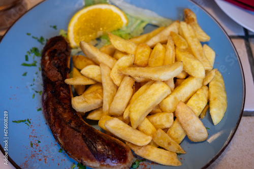 Fried fries potatoes with grilled meat German sausage served in old restaurant in Germany