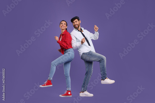 Happy couple dancing together on violet background
