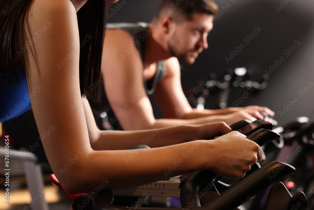 Woman and man training on exercise bikes in fitness club, closeup Woman and man training on exercise bikes in fitness club, closeup