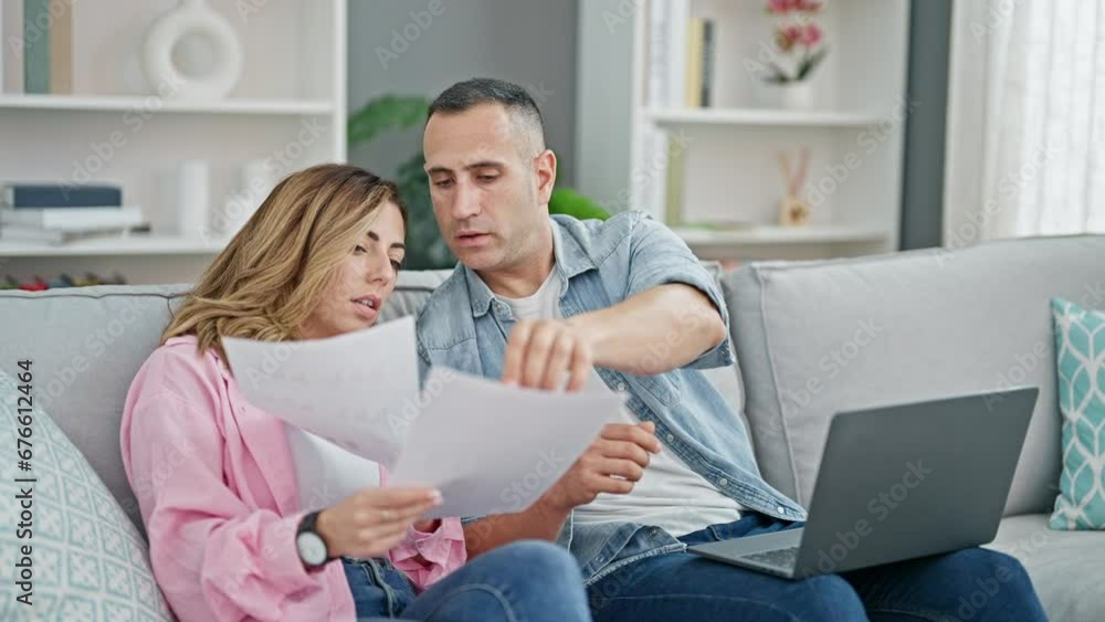 Man and woman couple using laptop reading document at home Man and woman couple using laptop reading document at home