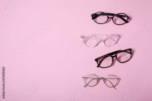 Different stylish glasses on pink background, flat lay. Space for text