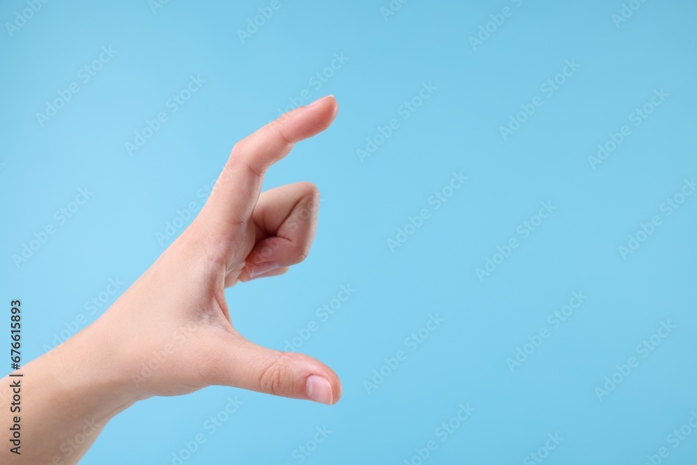 Woman holding something in hand on light blue background, closeup. Space for text