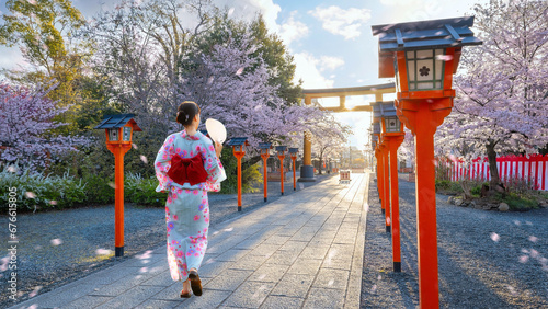 Young Japanese woman in traditional Yukata dress strolls at  Hirano-jinja Shrine during full bloom cherry blossom season photo