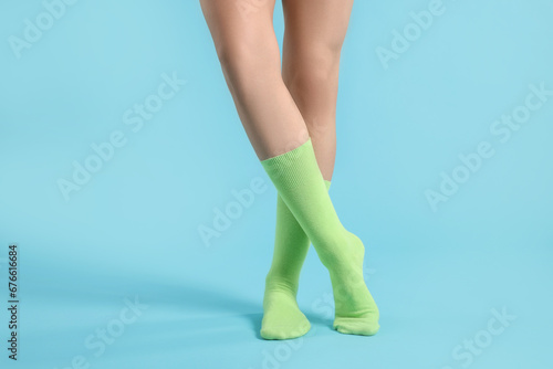 Woman in stylish lime socks on light blue background, closeup