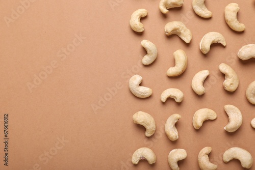Many tasty cashew nuts on pale brown background, top view. Space for text