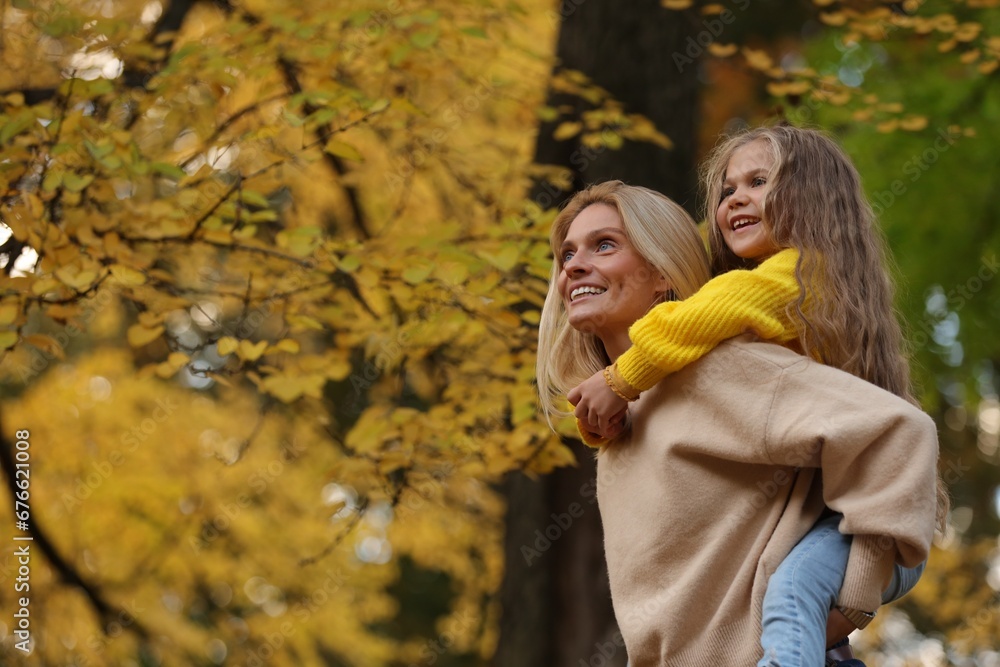 Portrait of happy mother and daughter in autumn park. Space for text Portrait of happy mother and daughter in autumn park. Space for text