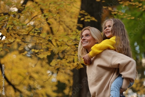 Portrait of happy mother and daughter in autumn park. Space for text