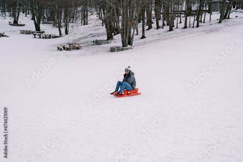Smiling man in sunglasses going down hill on sled