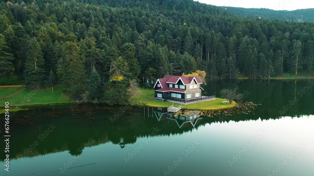 The drone in the forest moves through the trees and sees the image of the house on the lake. Gorgeous autumn colors. Bolu, Turkey. The drone in the forest moves through the trees and sees the image of the house on the lake. Gorgeous autumn colors. Bolu, Turkey.