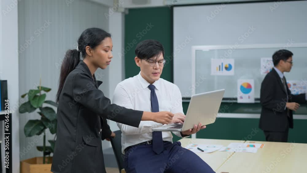 asian business man sitting on table holding laptop computer talking to worker woman standing in office . colleagues discussing project . brainstorming asian business man sitting on table holding laptop computer talking to worker woman standing in office . colleagues discussing project . brainstorming