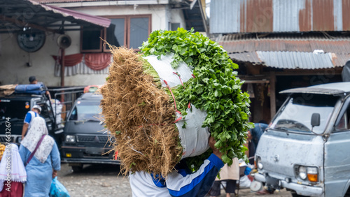 a worker is lifting celery with a sack in a traditional market in Indonesia photo