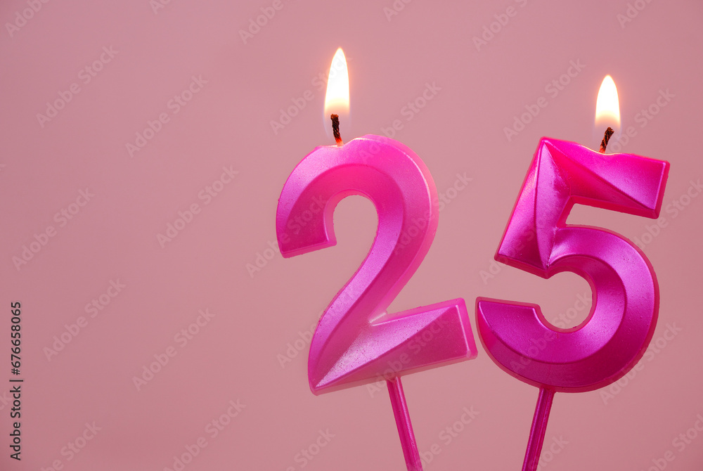 Pink birthday candles burning and melting on pink background. Copy space for text. Number 25. Pink birthday candles burning and melting on pink background. Copy space for text. Number 25.