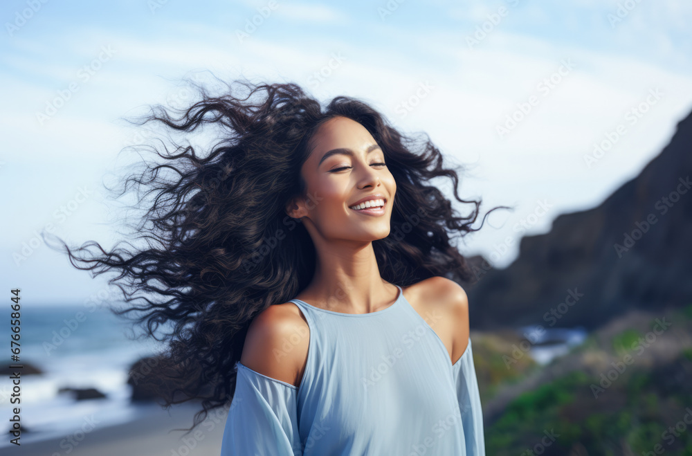 Young woman with eyes closed enjoying her freedom by the sea coast