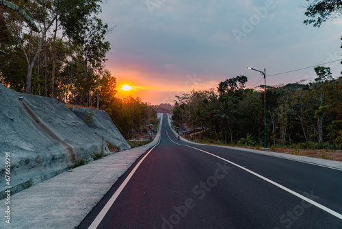 Smooth black asphalt road that cuts through the limestone hill area. This asphalt road with a central line connecting the provinces is very beautiful when the sun sets at the end of the asphalt road