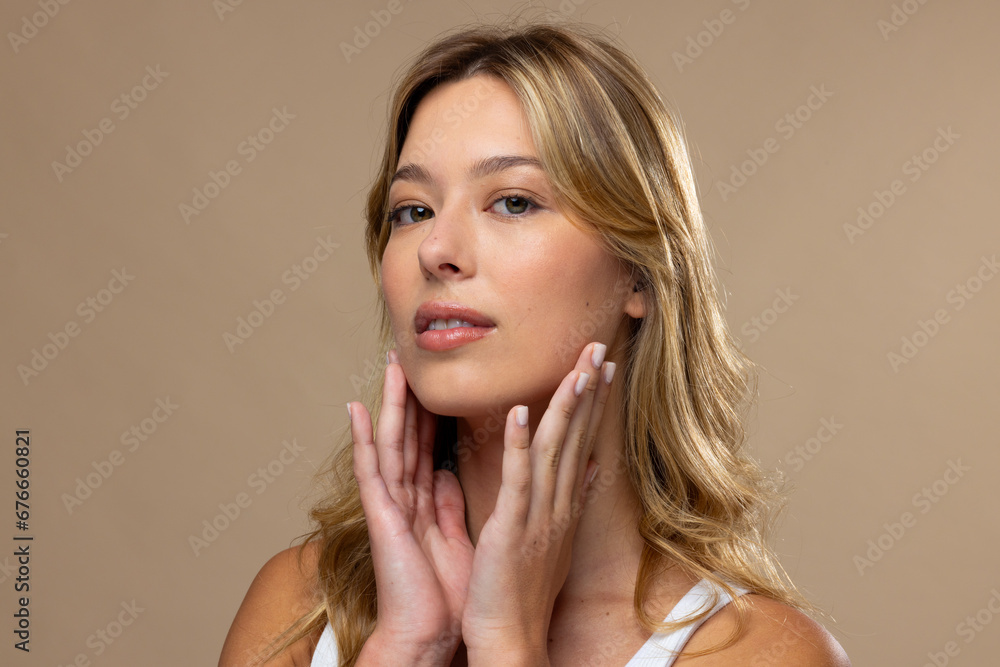 Portrait of caucasian woman wearing natural makeup and beige nail polish on beige background Portrait of caucasian woman wearing natural makeup and beige nail polish on beige background