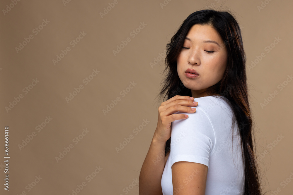 Asian woman wearing natural makeup and white t-shirt on beige background, copy space Asian woman wearing natural makeup and white t-shirt on beige background, copy space